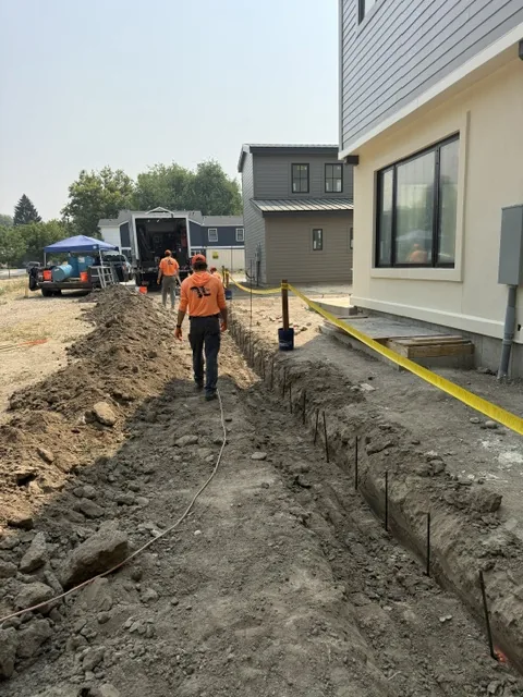 Crew working in a shoring trench beside a home under construction
