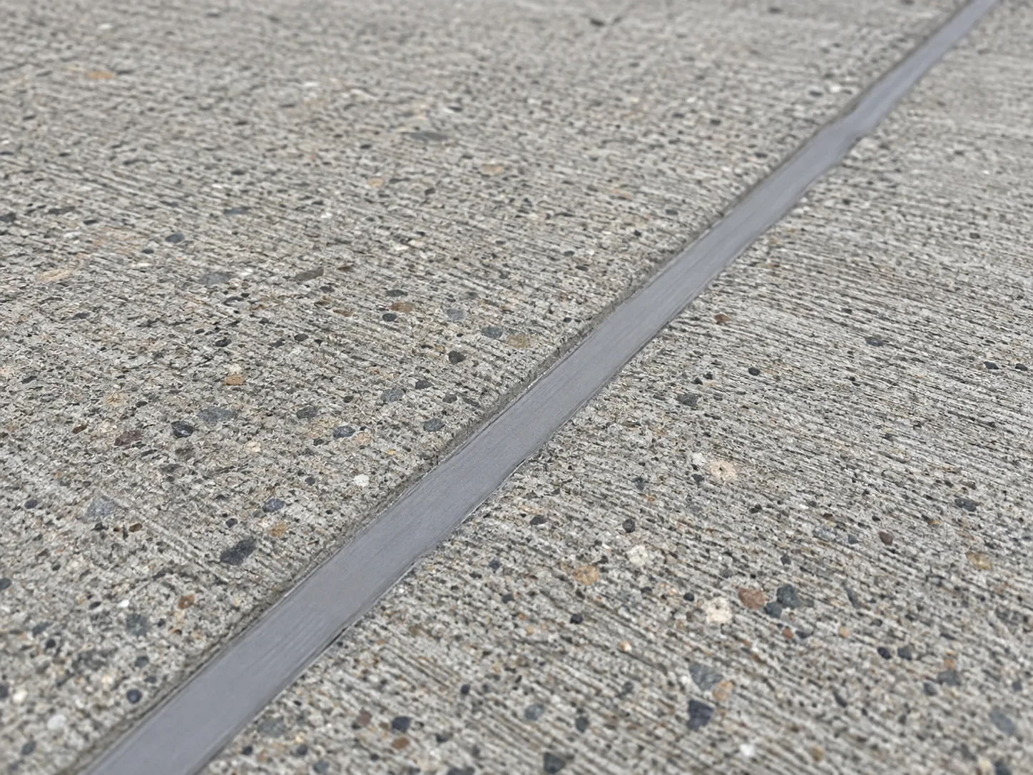 Gray sealant filling a joint between textured concrete slabs